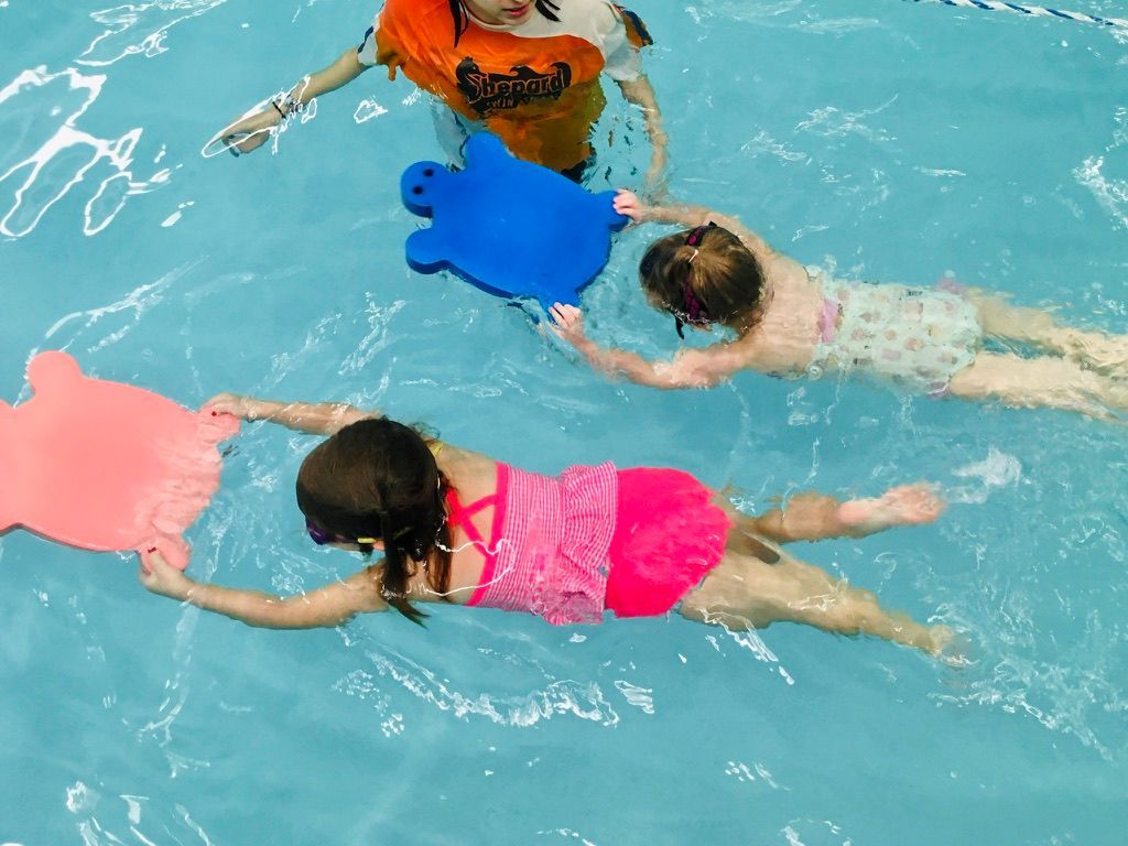 A group of children are swimming in a pool with floats.