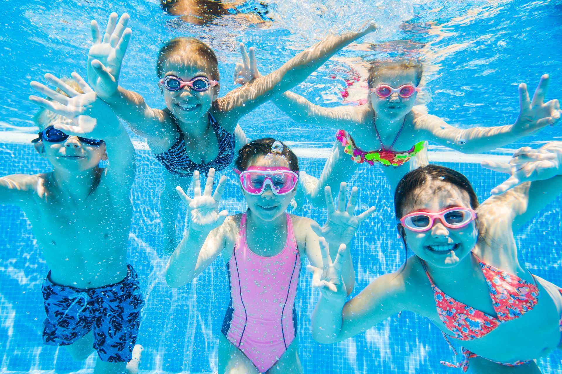 A group of children are swimming underwater in a swimming pool.