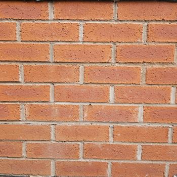 Brick wall with red-orange bricks laid in a running bond pattern, with light gray mortar joints.