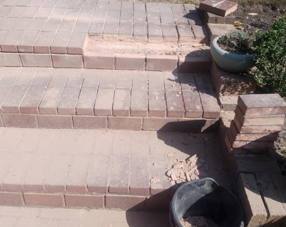 Brick steps being constructed; red bricks in progress, unfinished project, dirt.