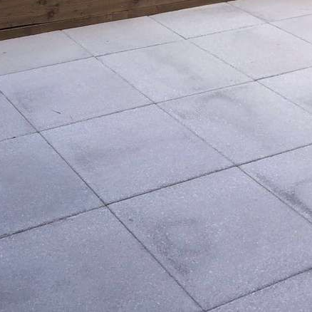 Square concrete pavers, lightly frosted, forming a patio or walkway.
