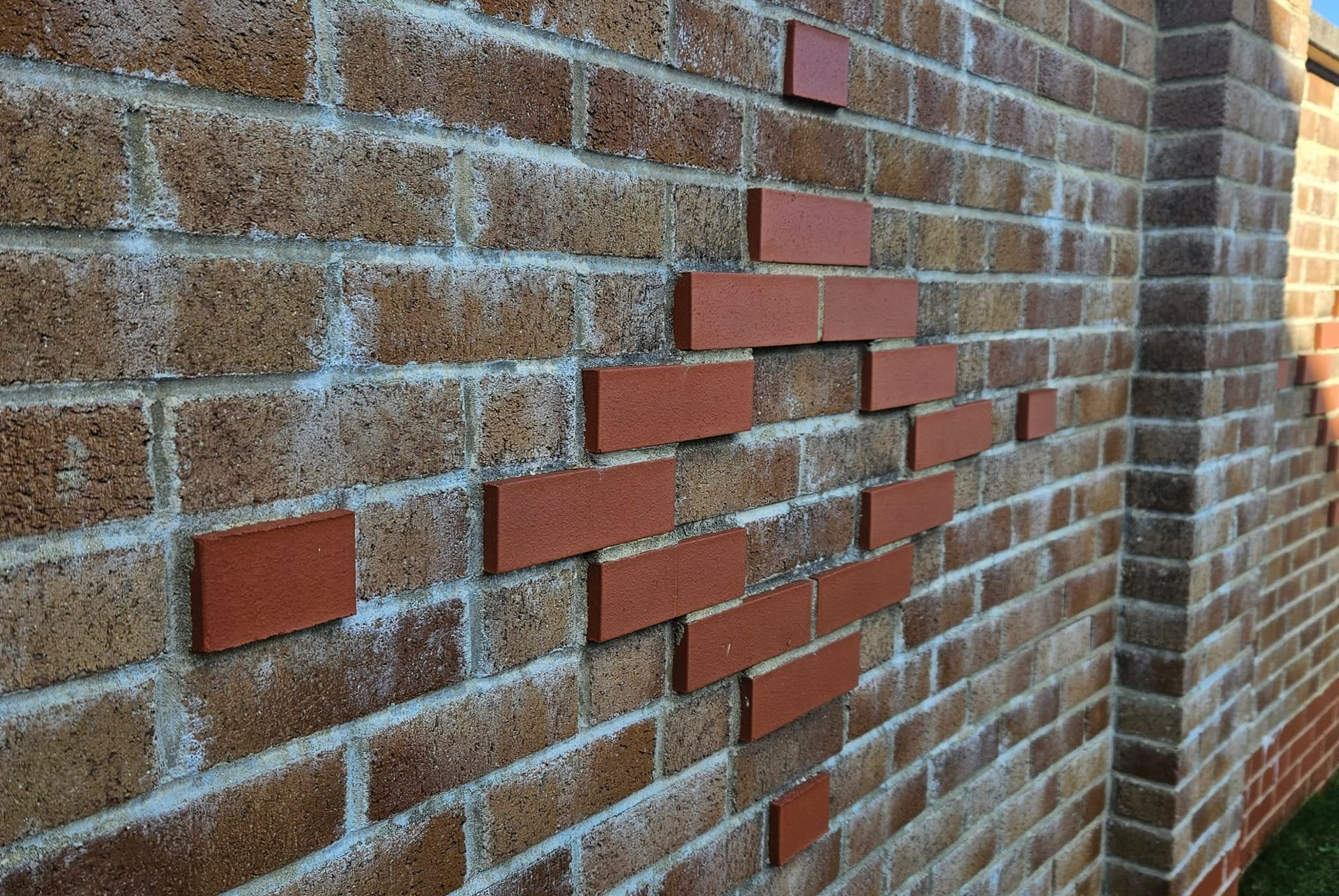 Brick wall with a diamond-shaped pattern of red bricks against a tan brick background.