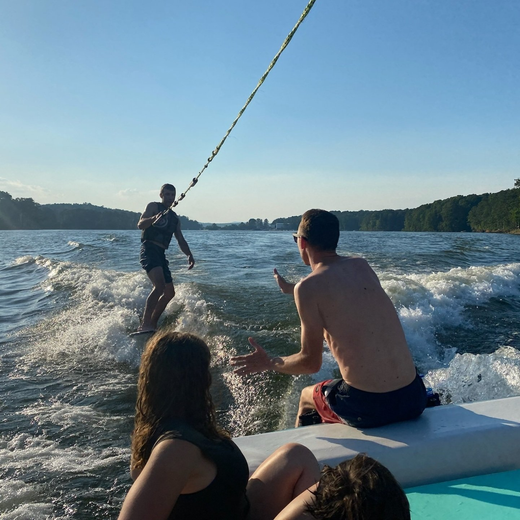 A group of people on a boat watching a man wakeboard