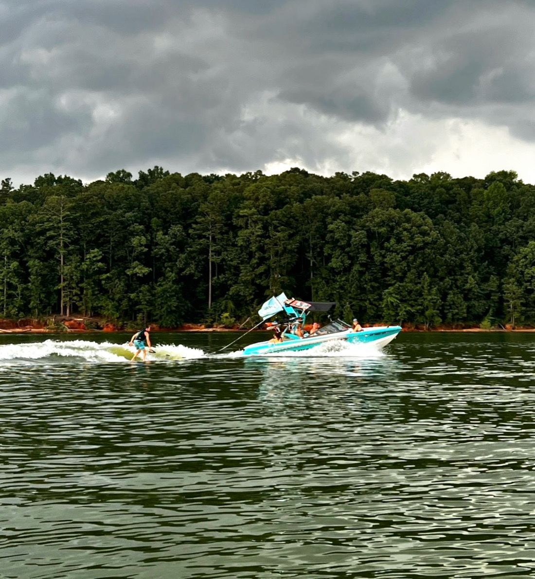 Two boats are floating on a lake with trees in the background