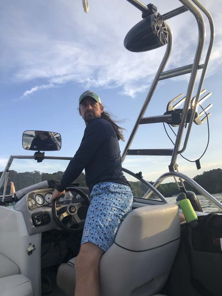 A man is sitting in the driver 's seat of a boat.