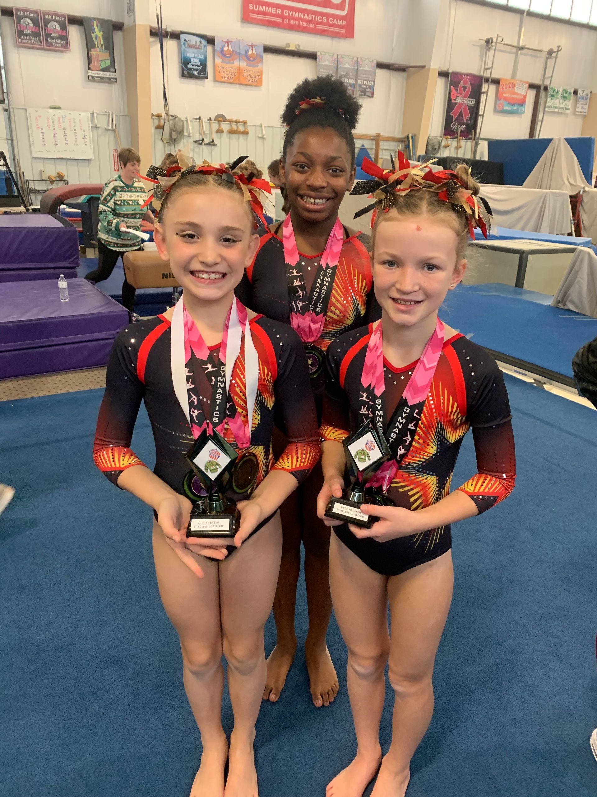 Three young girls are standing next to each other holding medals.