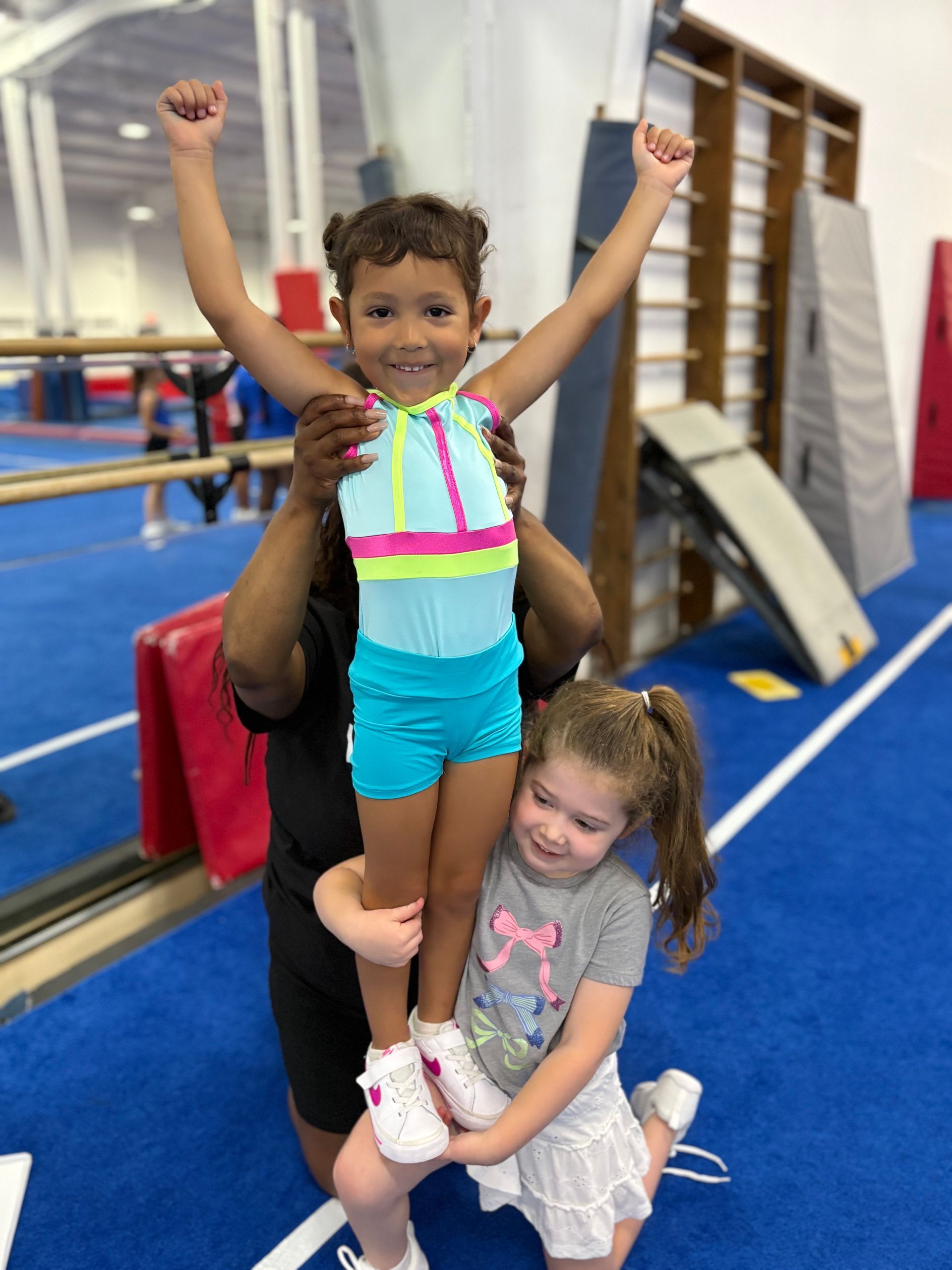 Two young girls are sitting on a bench in a gym.
