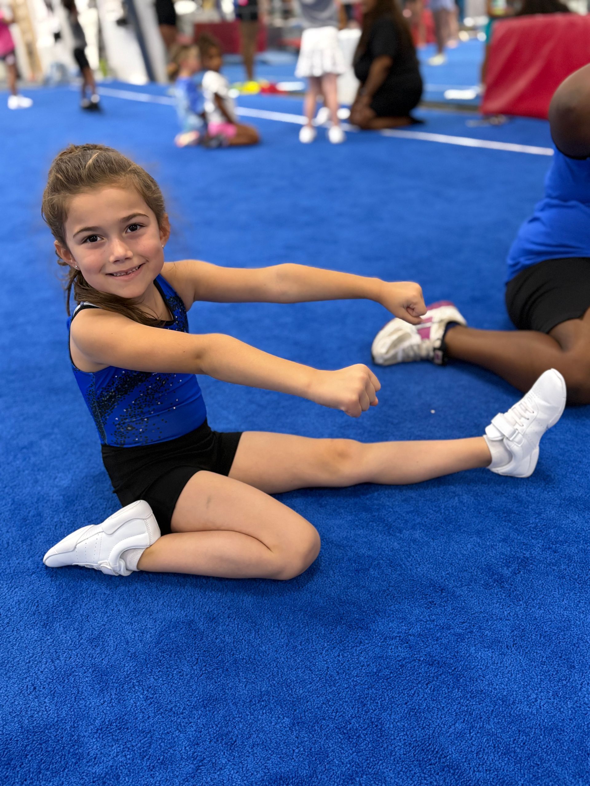 A woman is holding a little girl in the air in a gym.