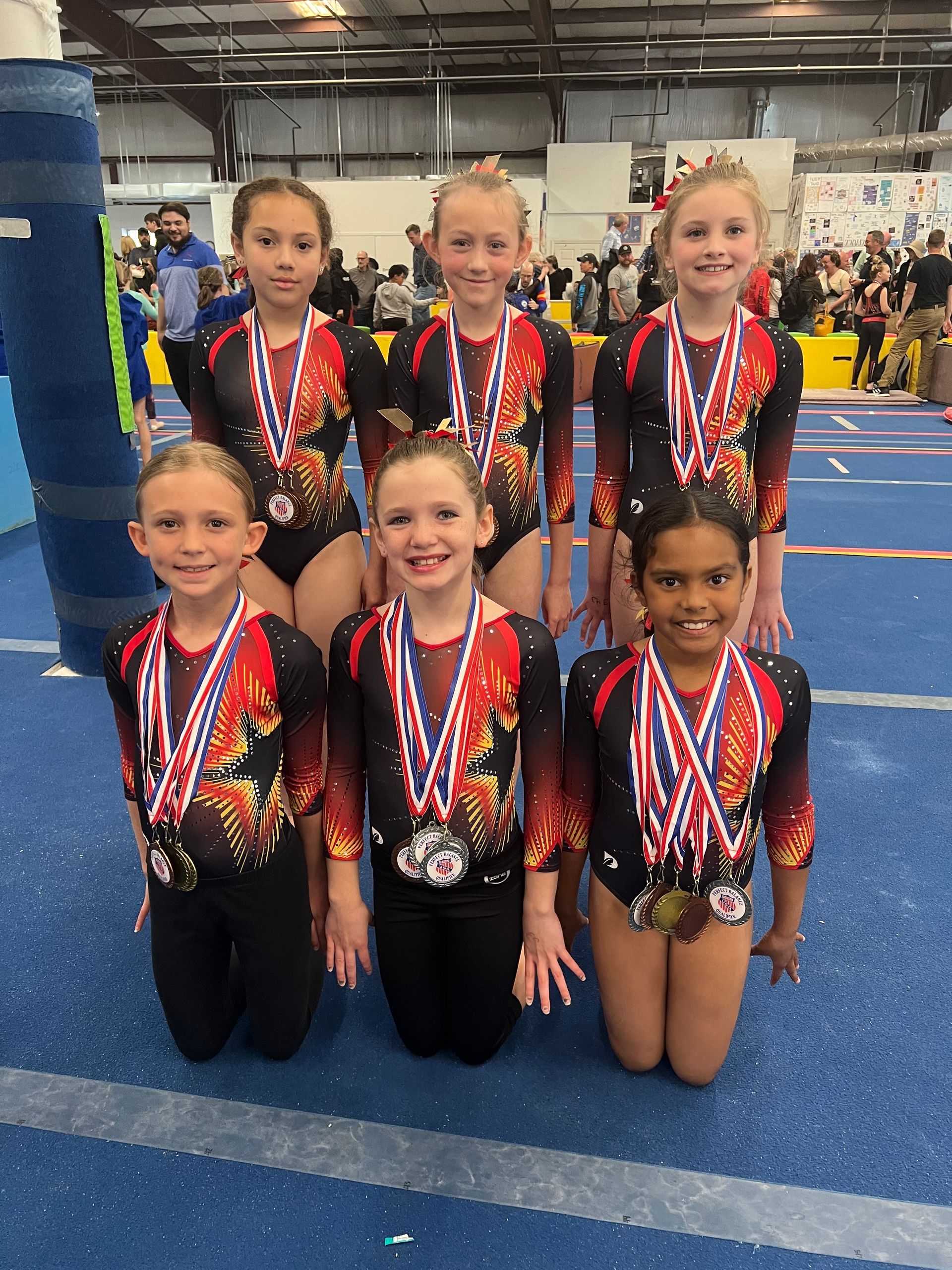 A group of young girls wearing medals are posing for a picture.