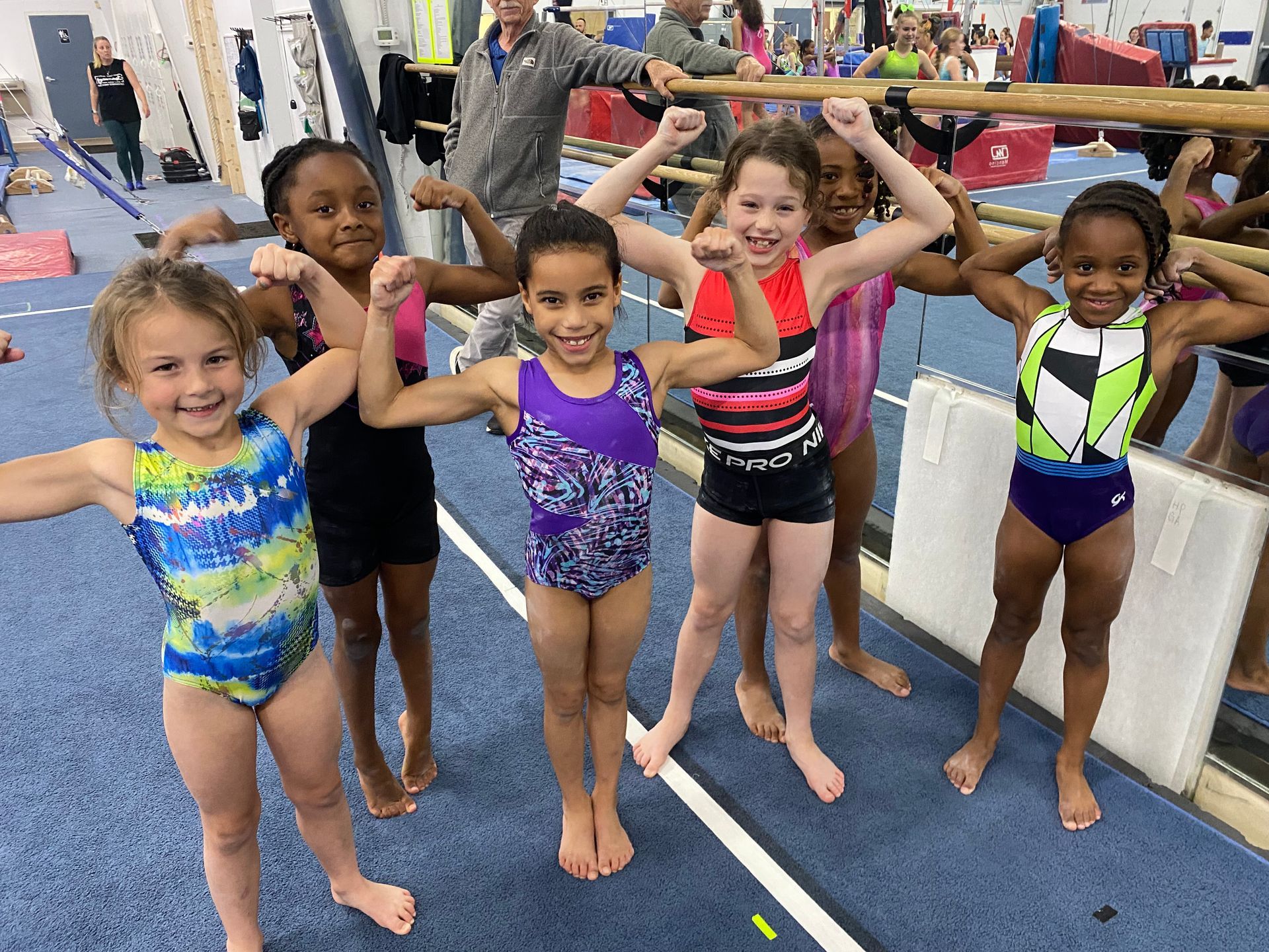 A group of young girls are posing for a picture in a gym.
