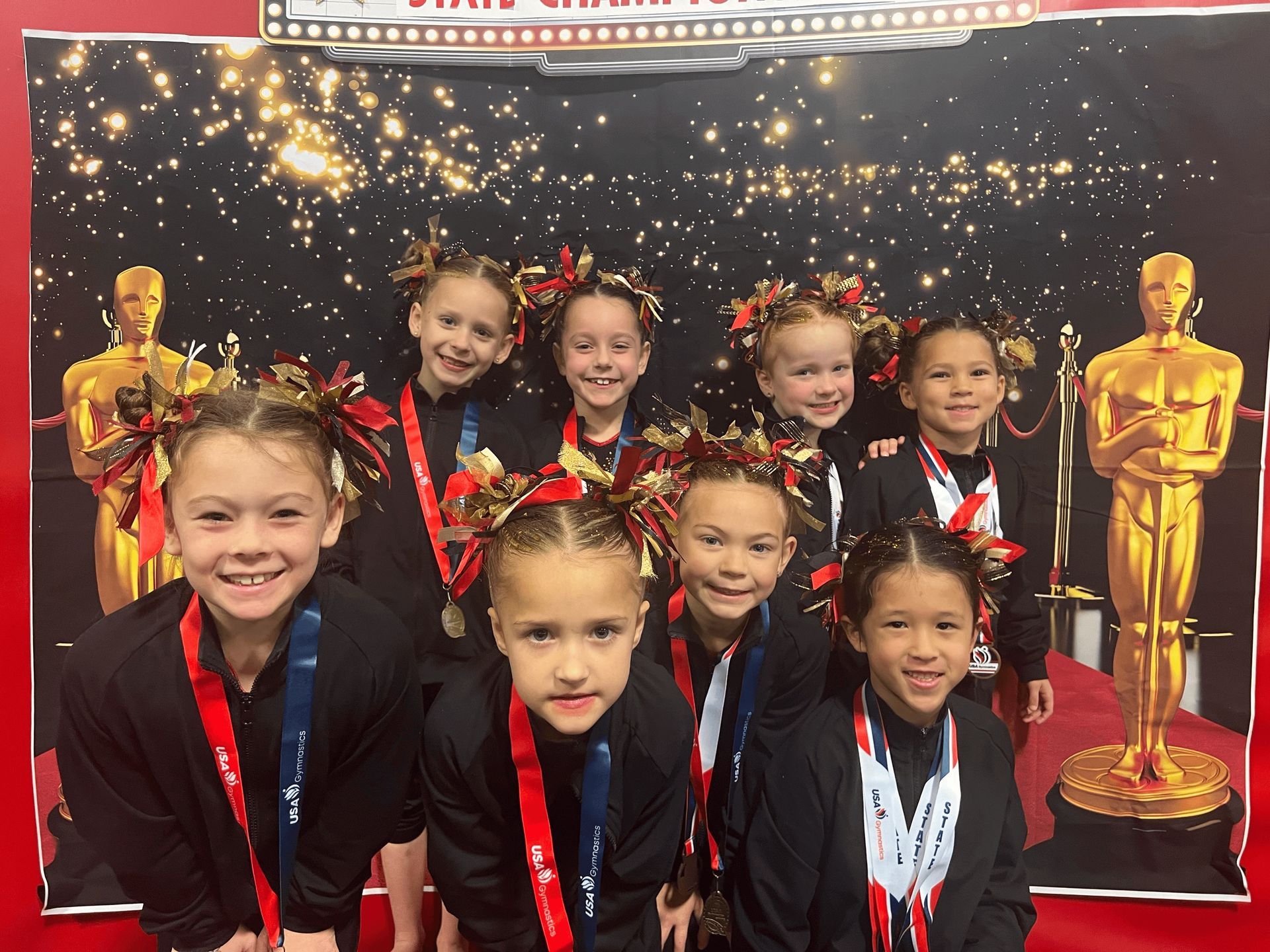 Three young girls are standing next to each other holding medals.
