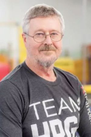 A man with glasses and a beard is wearing a team shirt.