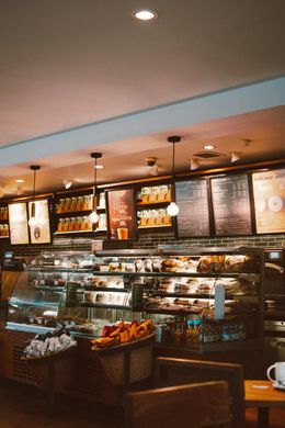 Inside a Starbucks coffee shop: pastries in a glass display case, menu boards, and overhead lighting.