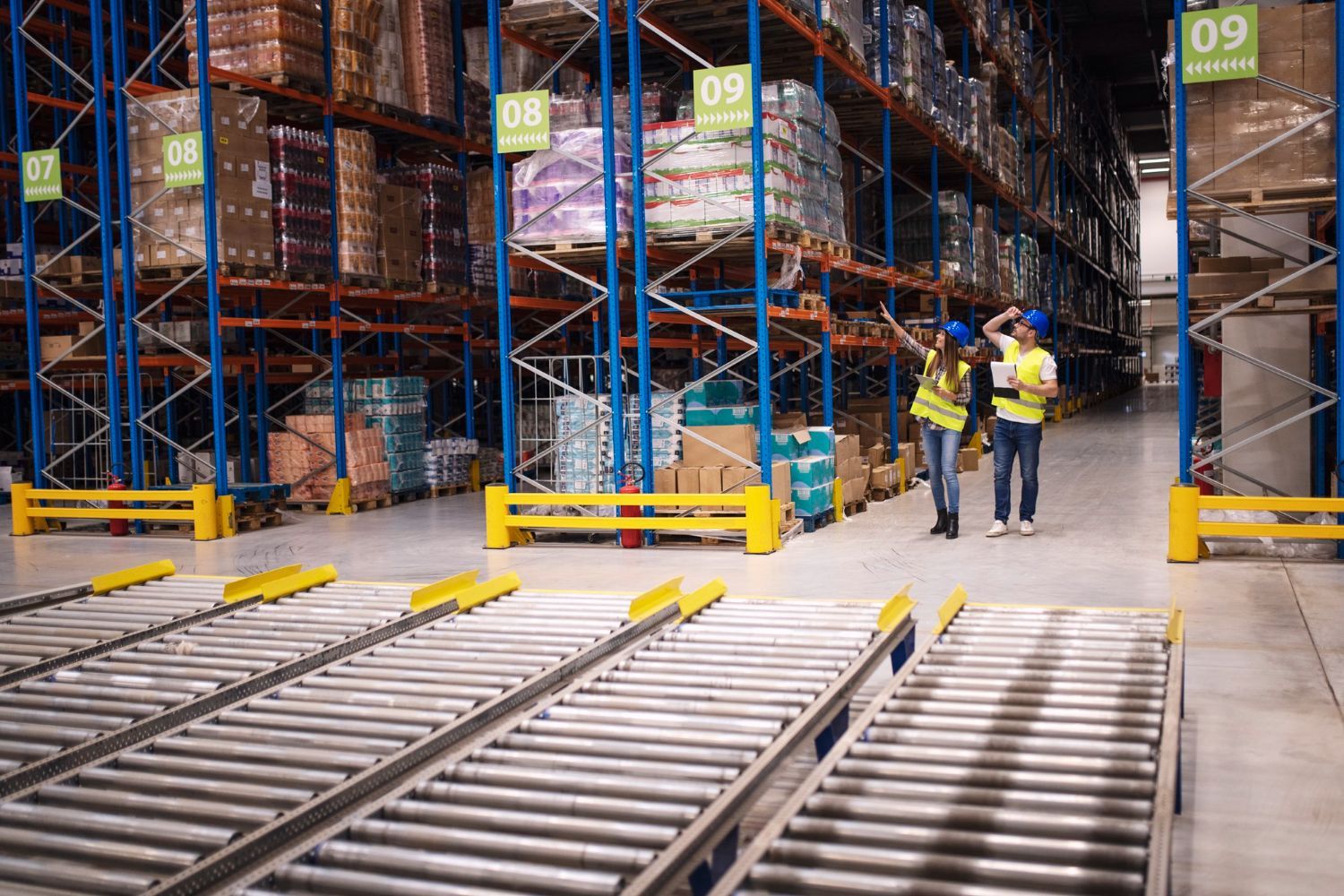 Two men are walking through a large warehouse with conveyor belts.