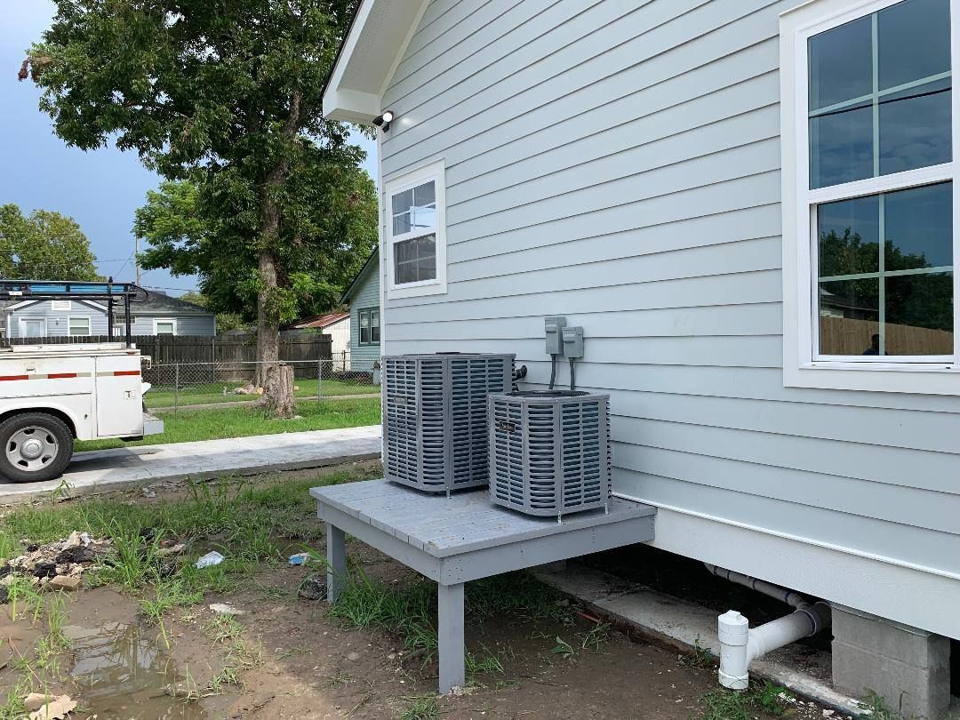 There are two air conditioners on the side of a house.