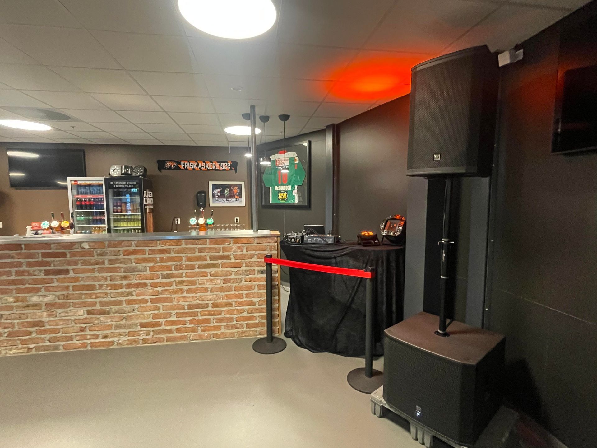 et rom med murvegg, bar, høyttaler og TV.