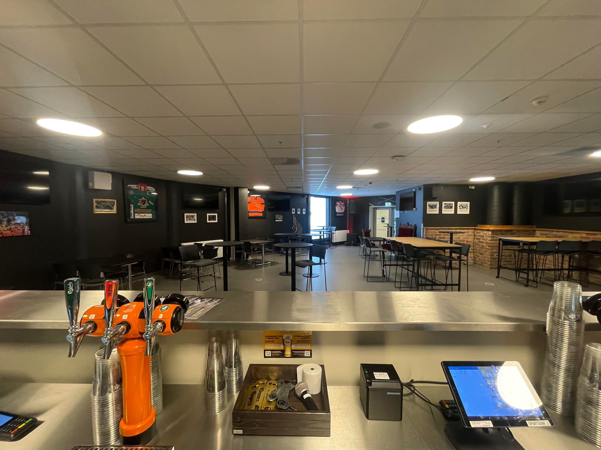 en restaurant med bar i rustfritt stål og bord og stoler.