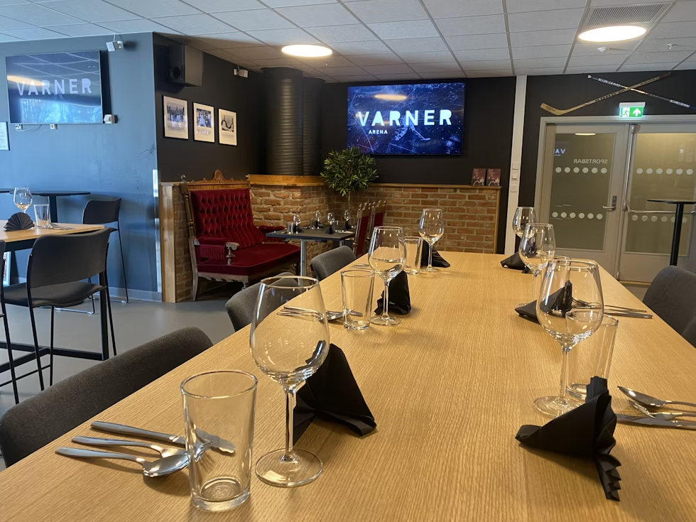 et langt trebord med glass vin og sølvtøy i en restaurant.