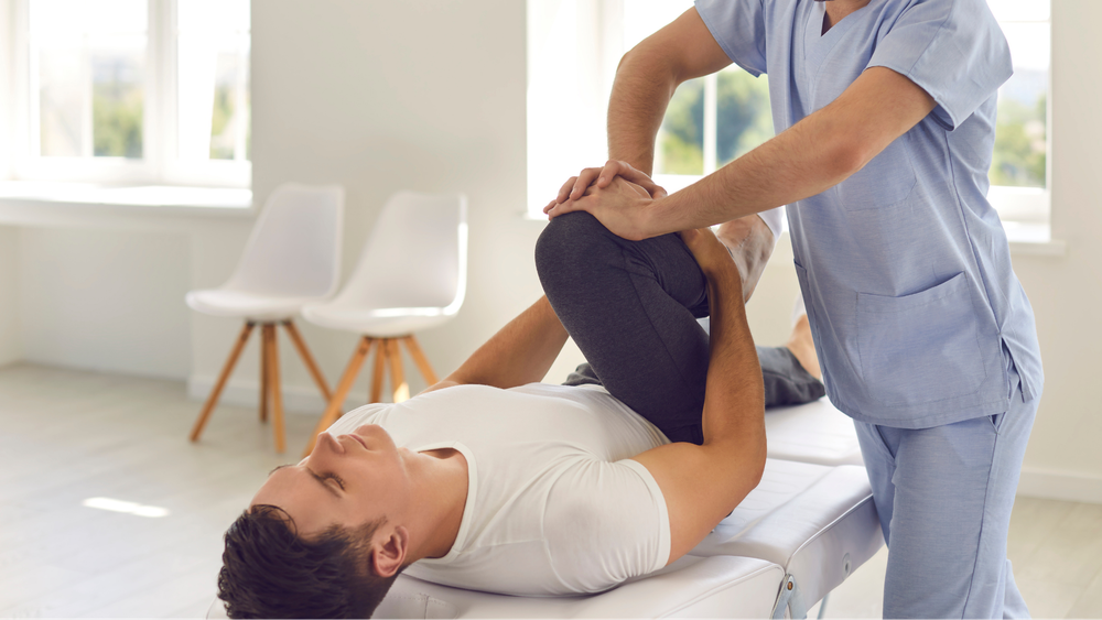 A man is laying on a table getting a massage from a nurse.