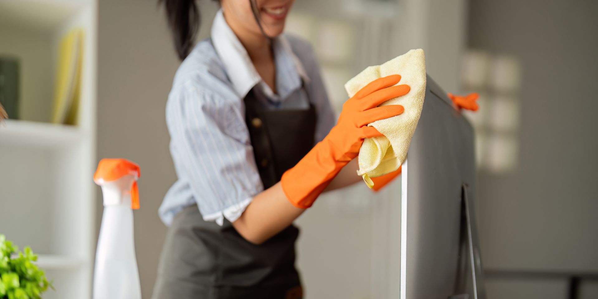 A Woman Wearing Orange Gloves is Cleaning a Refrigerator With a Cloth