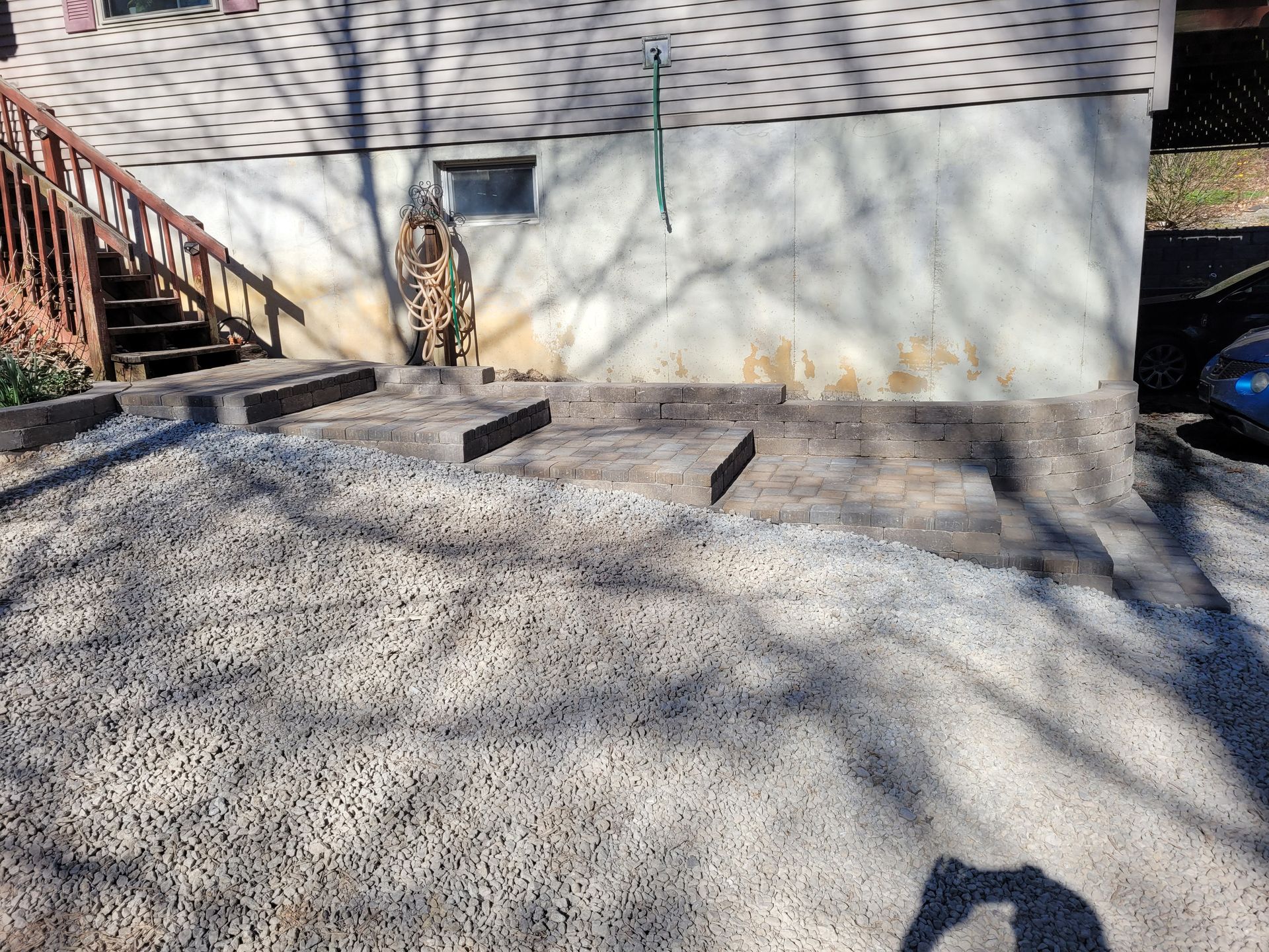 A house exterior showing a concrete foundation with gray retaining wall steps leading toward a wooden staircase.