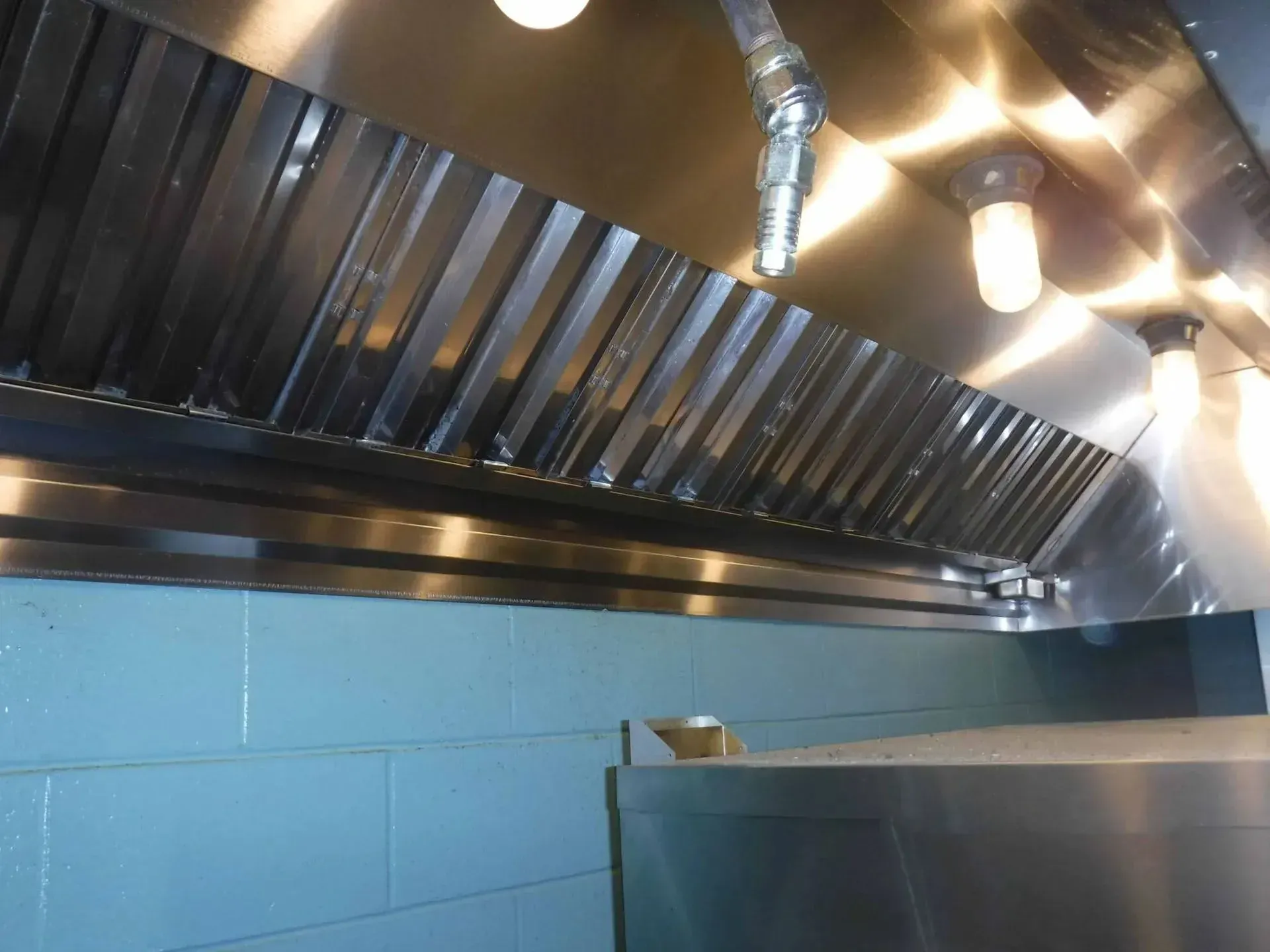 A stainless steel hood with a light hanging from it