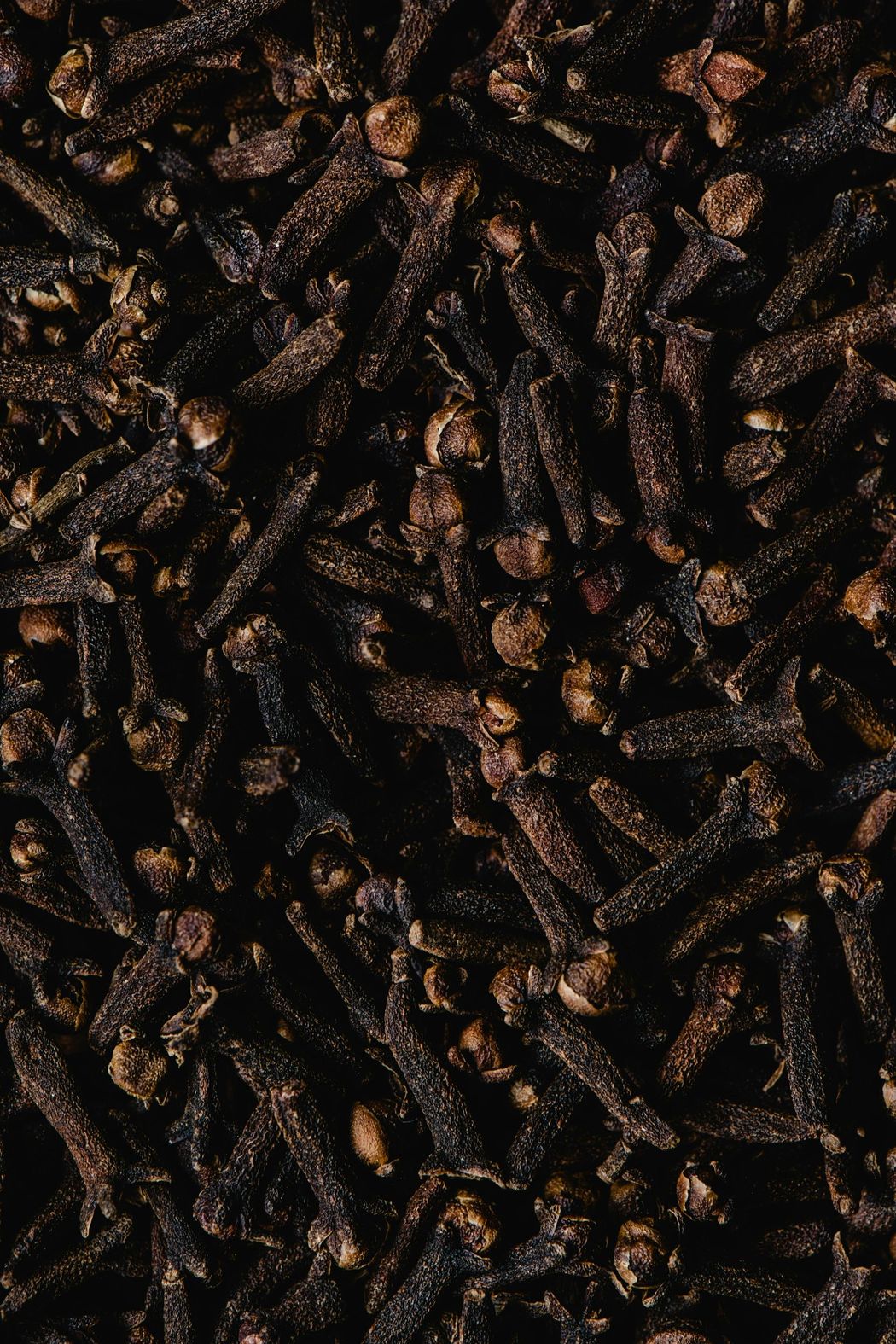 Close-up of dried cloves, dark brown color.