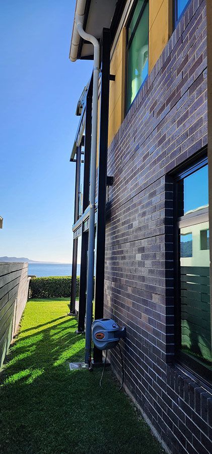 A Large Brick Building With A Drainpipe On The Side Of It — Dan's Pest Control in Kiama, NSW
