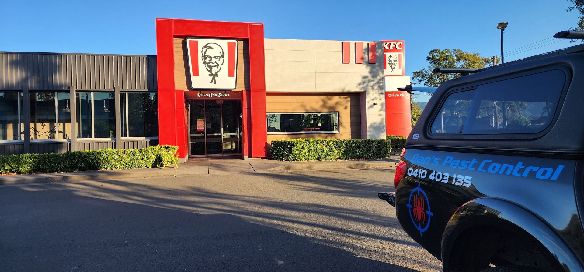 A Black Truck is Parked in Front of a KFC Restaurant — Dan’s Pest Control in Woonona, NSW