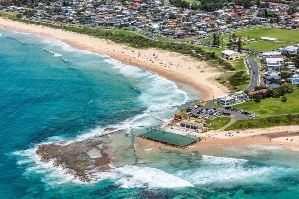 An Aerial View of a Beach With Waves Crashing on the Shore — Dans Pest Control in Woonona, NSW