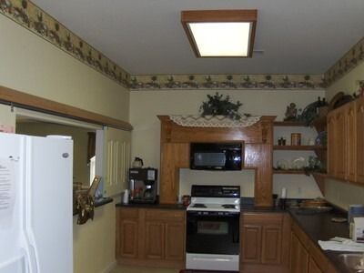 Kitchen with light-colored cabinets, microwave over a stove, and a framed opening.