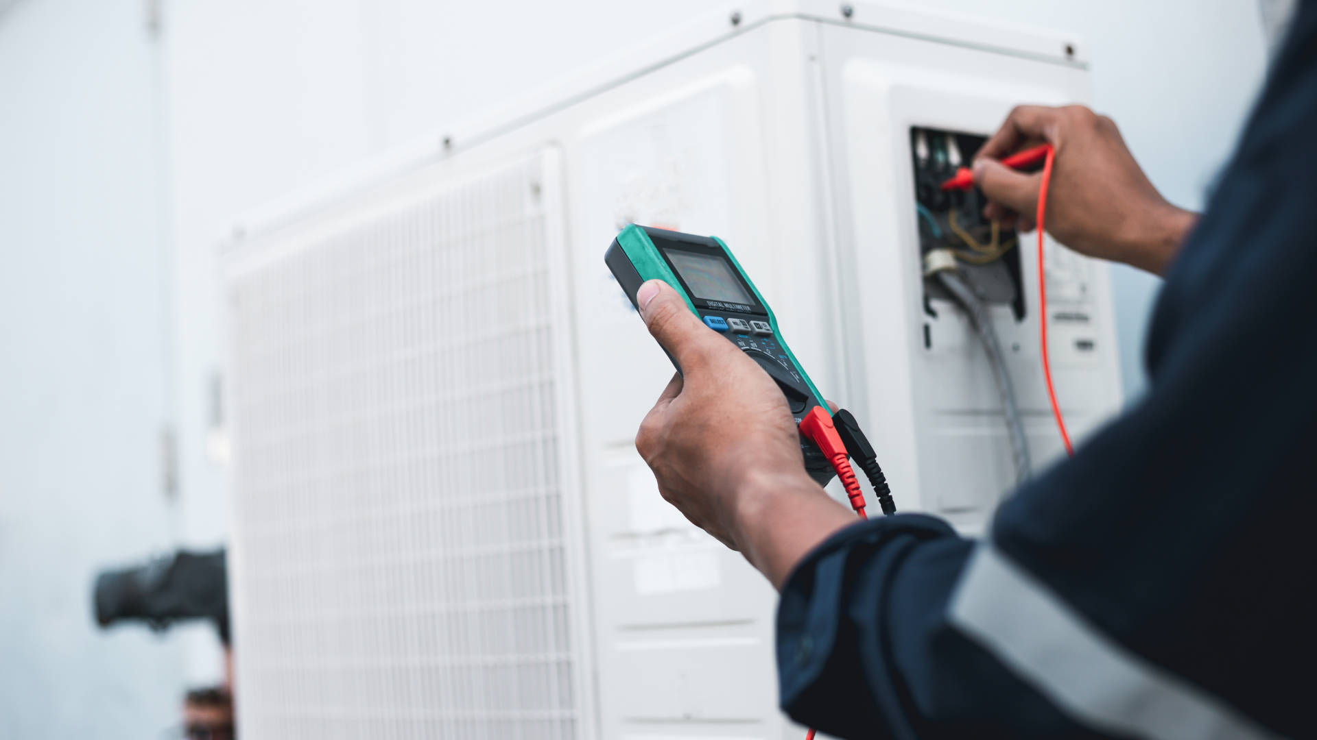 A man is using a multimeter to test an air conditioner.