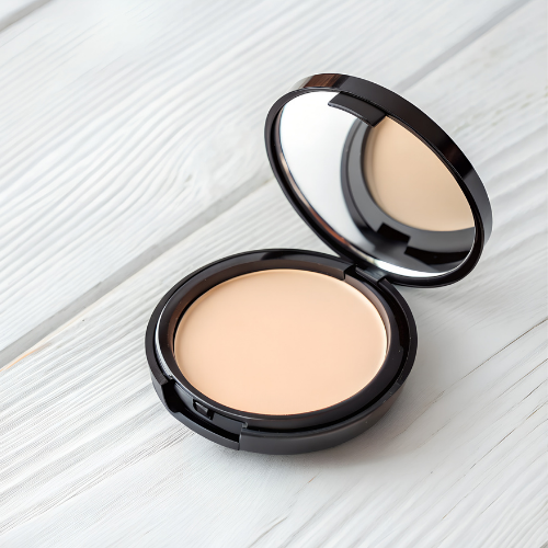 Open compact of beige face powder and mirror on a light wood surface.