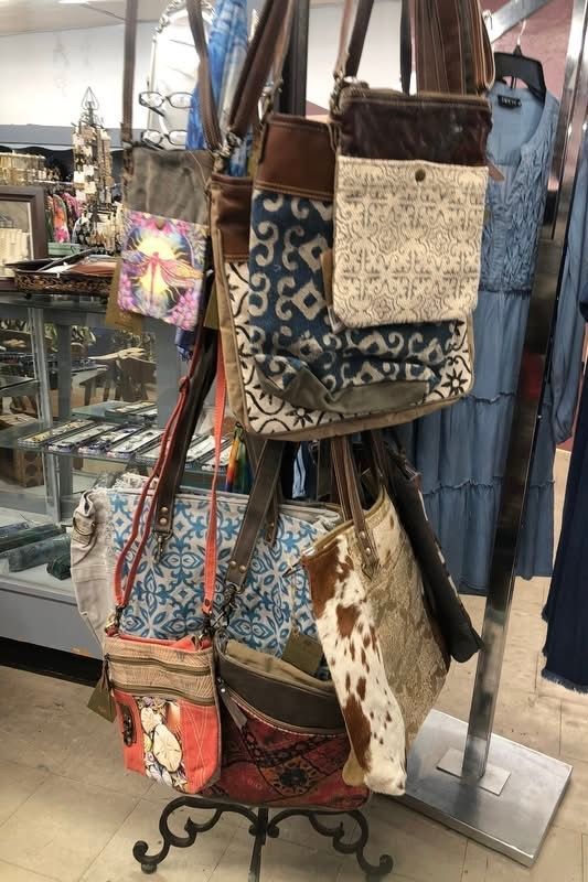 Yellow sundress, sandals, purse, sunglasses, and jewelry on a white wooden surface.