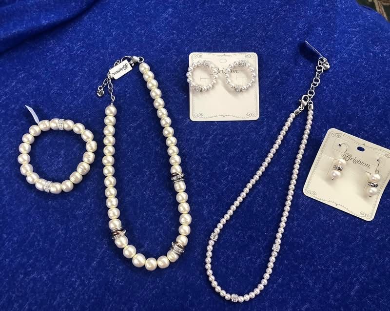 Woman wearing gold jewelry, including necklaces and rings, against a beige background.