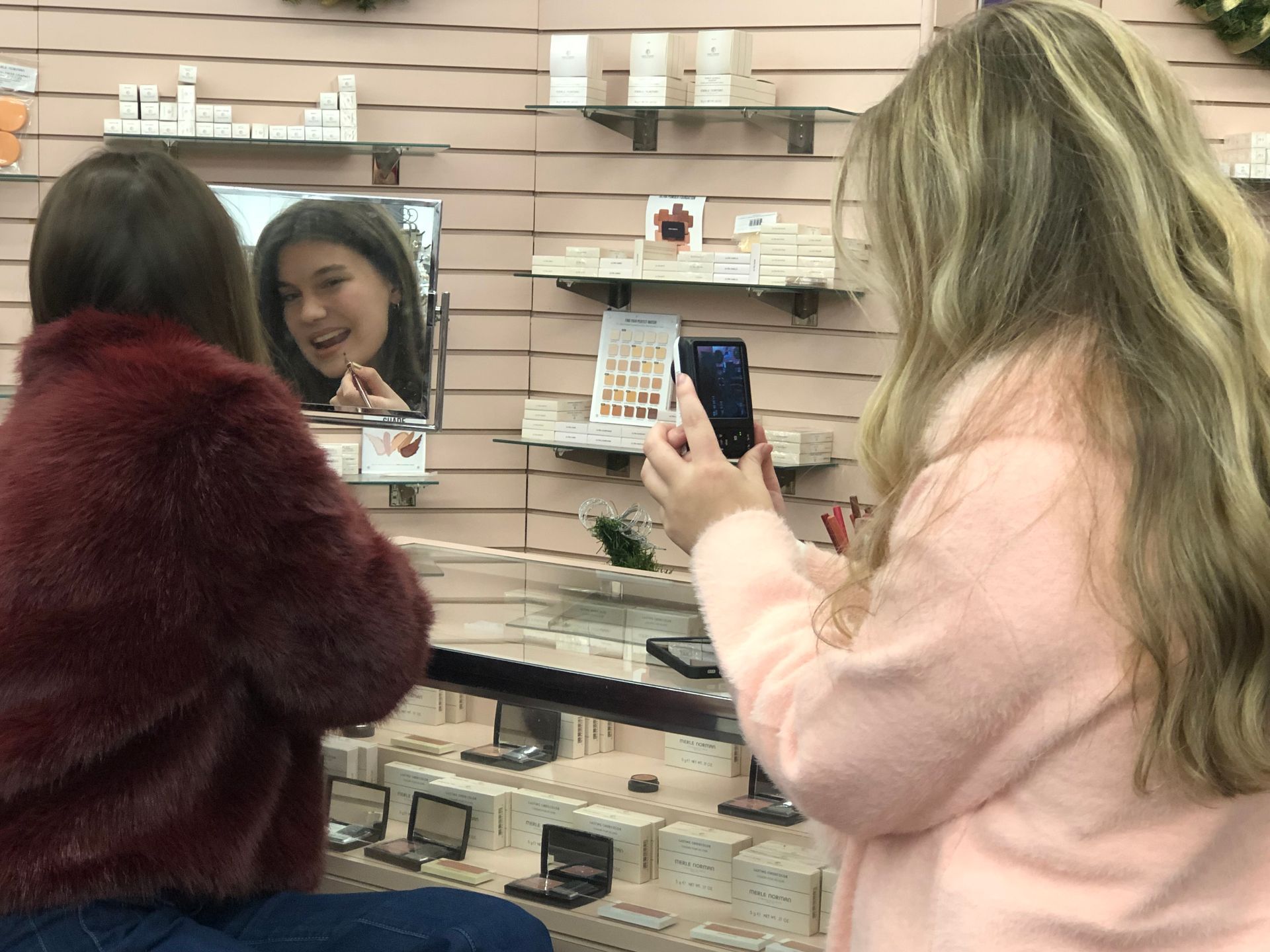 Woman wearing multiple gold necklaces and rings, posing with hands near face.