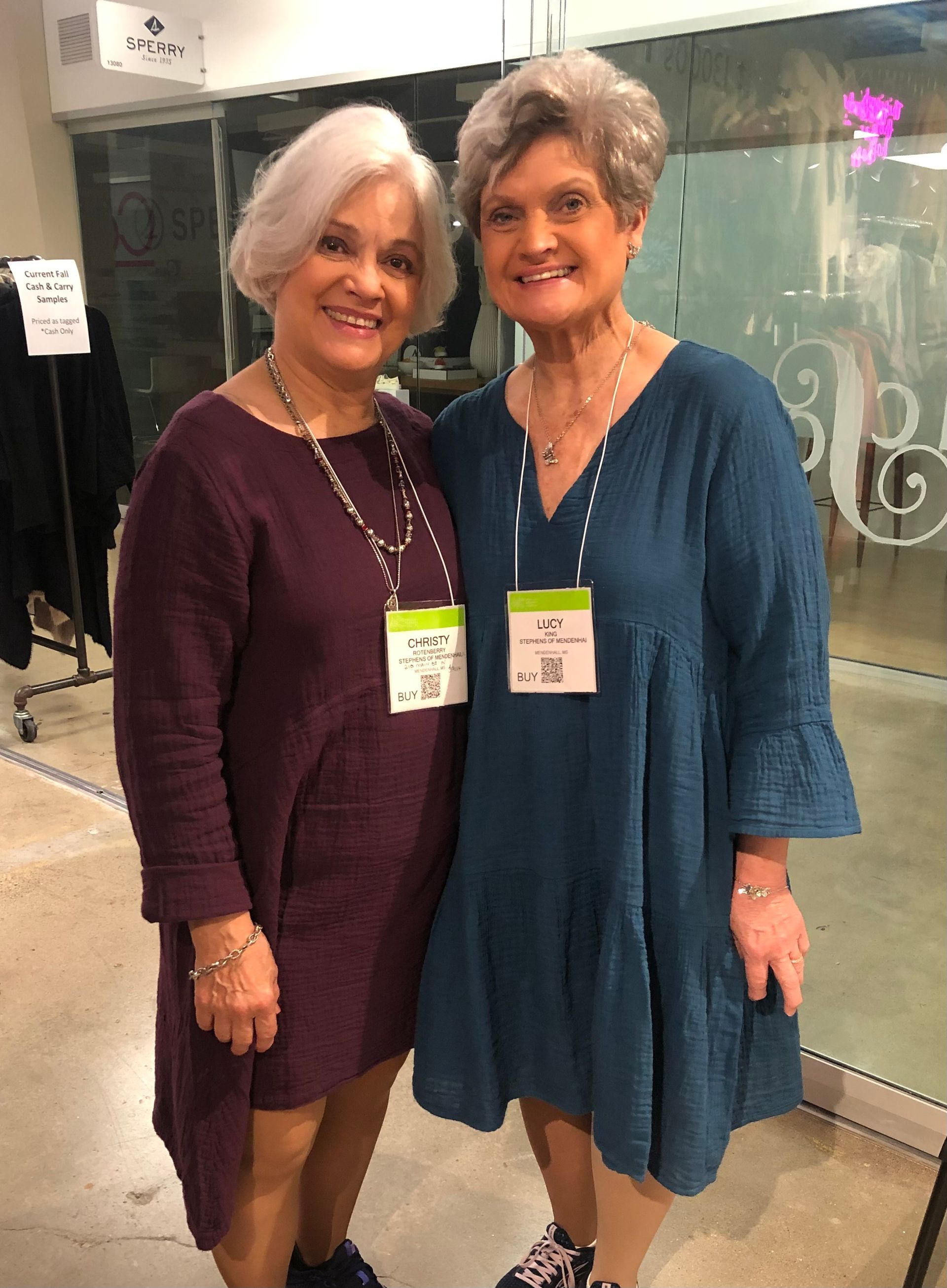 Necklace and earring sets on a black display stand. Purple and blue pendant necklaces and matching earrings.