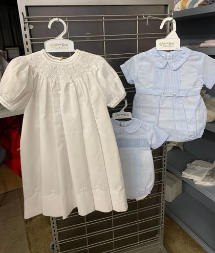 Striped baby clothes, socks, and rubber ducky toy on a white wood surface.