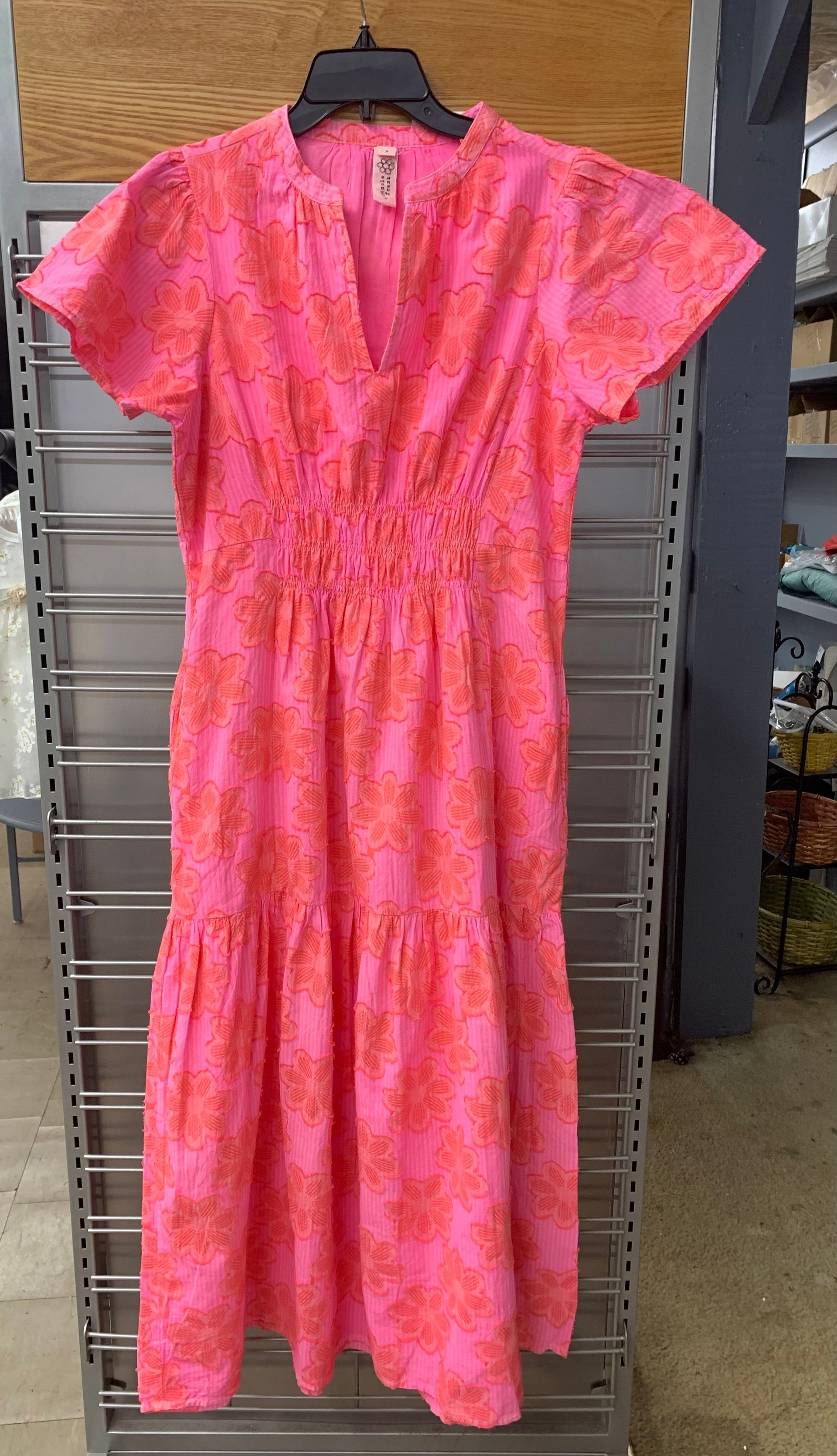 A bright pink midi dress with orange floral embroidery, short flutter sleeves, a V-neck, and a gathered, shirred waist.