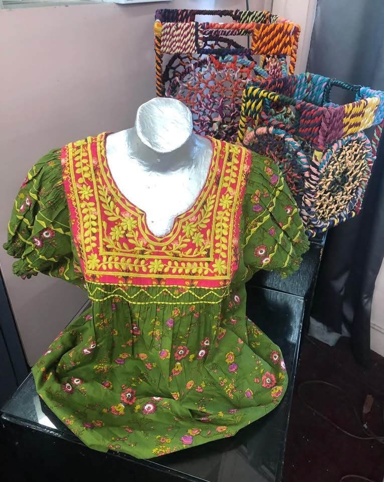 Cropped knit top with brown, blue, and white stripes, lying on a light green blazer and denim jeans.