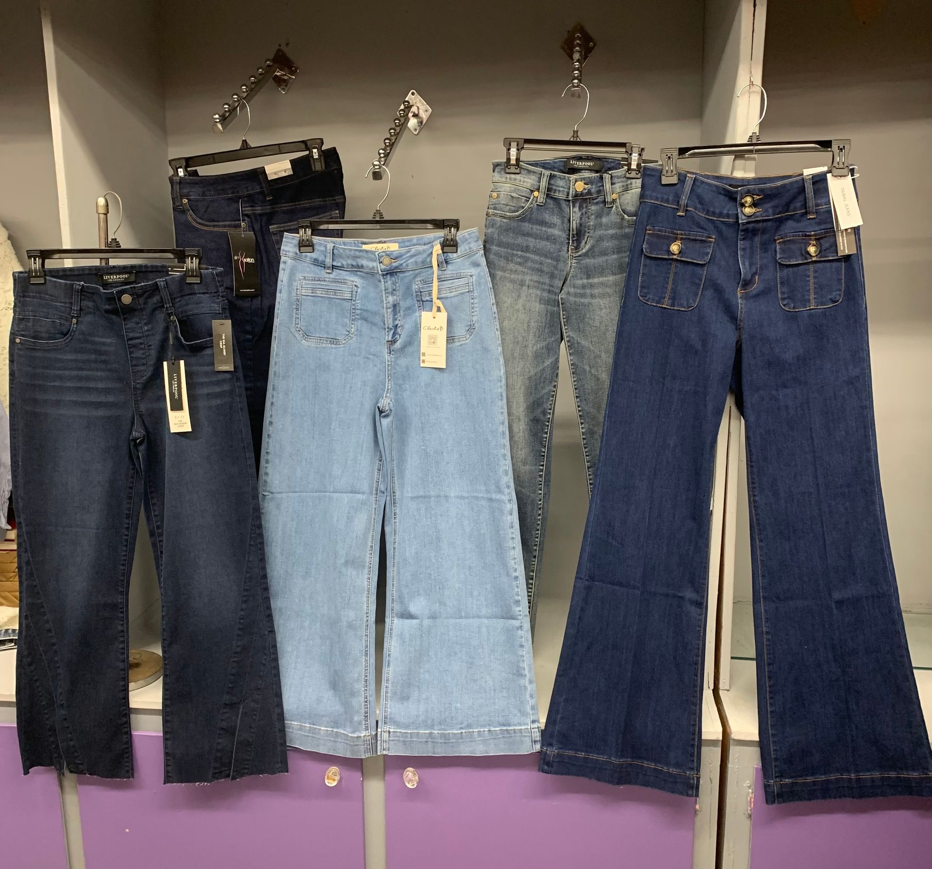 Person wearing blue jeans, hands near waistband, outdoors.