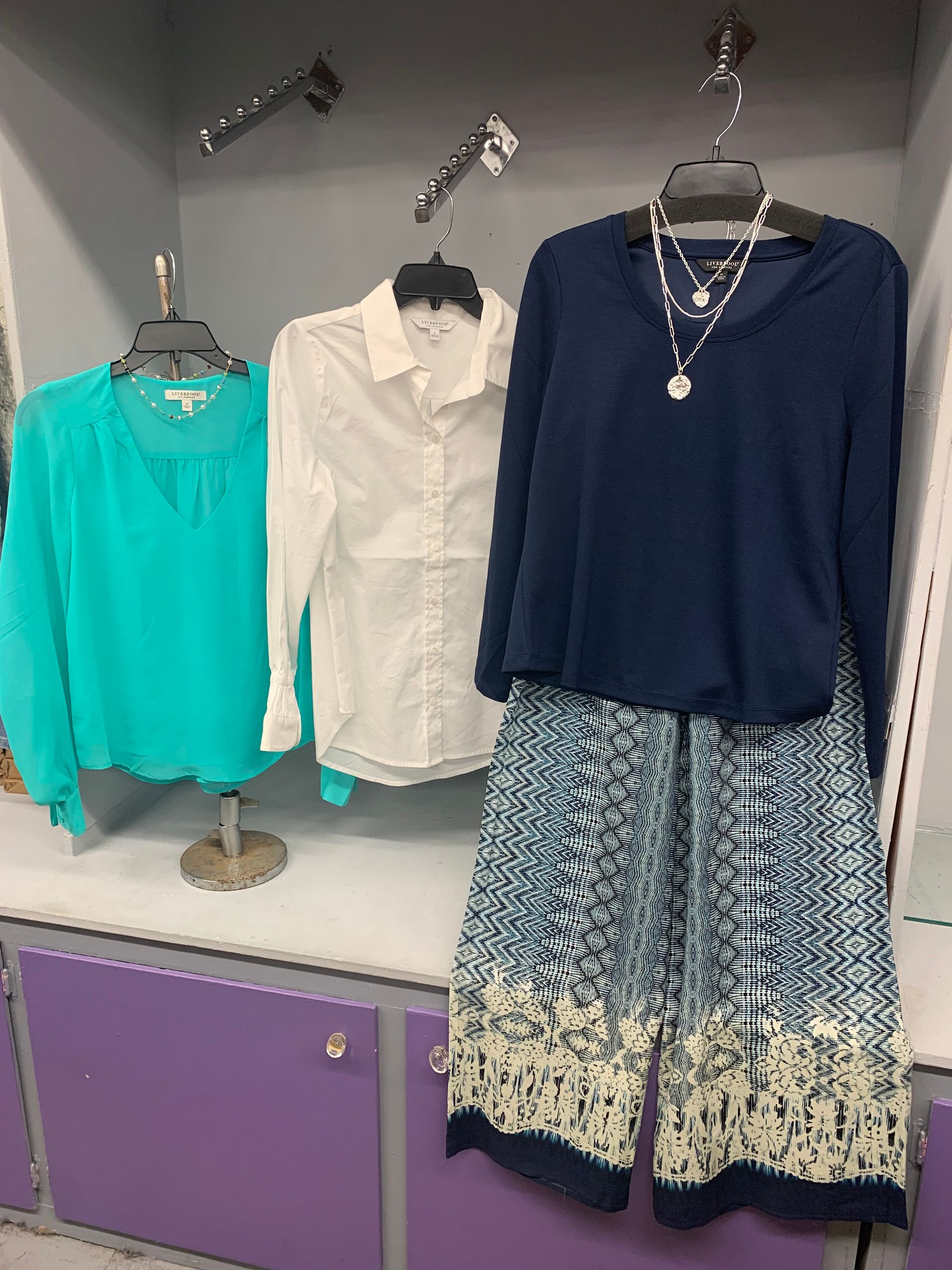 Man in black jeans and brown boots leaning against a gray wall.