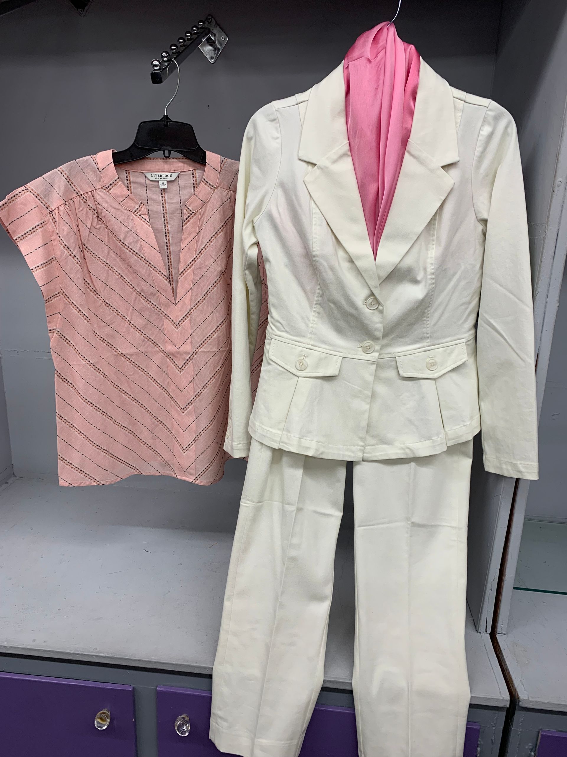 Man in black jeans and brown boots leaning against a gray wall.