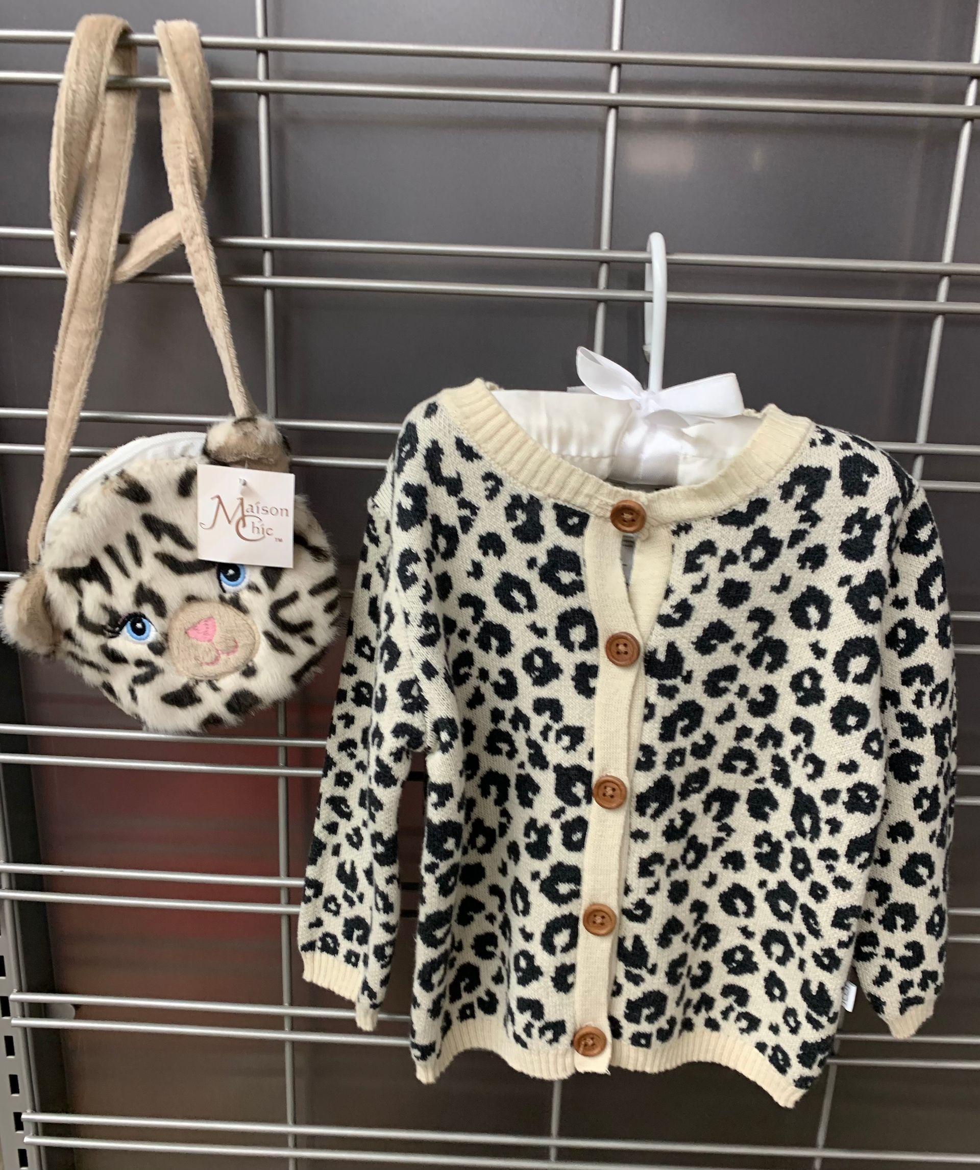 Striped baby clothes, socks, and rubber ducky on a white wooden surface.