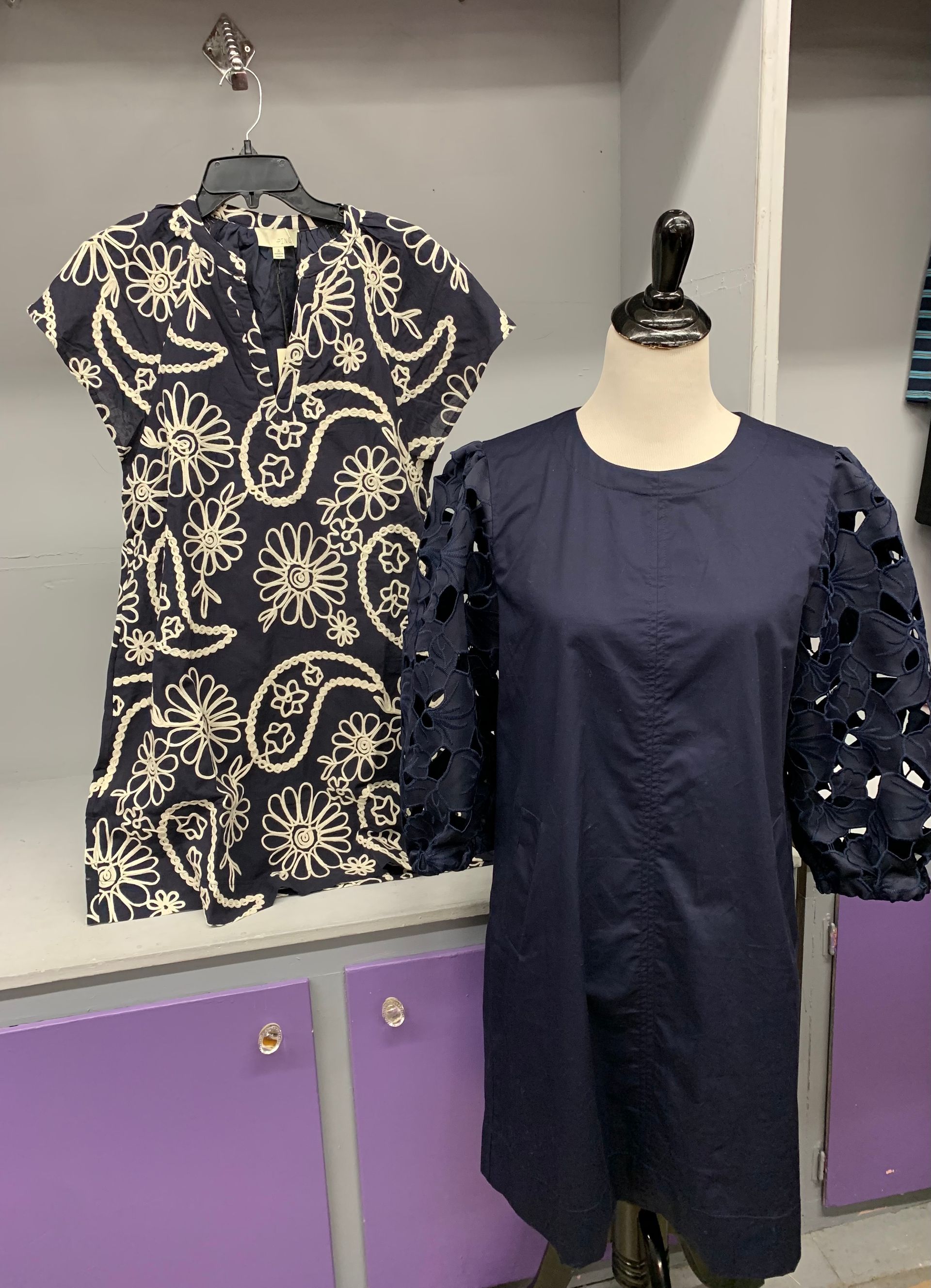 Woman in colorful patterned saree, red blouse, standing in front of a dark red wall.