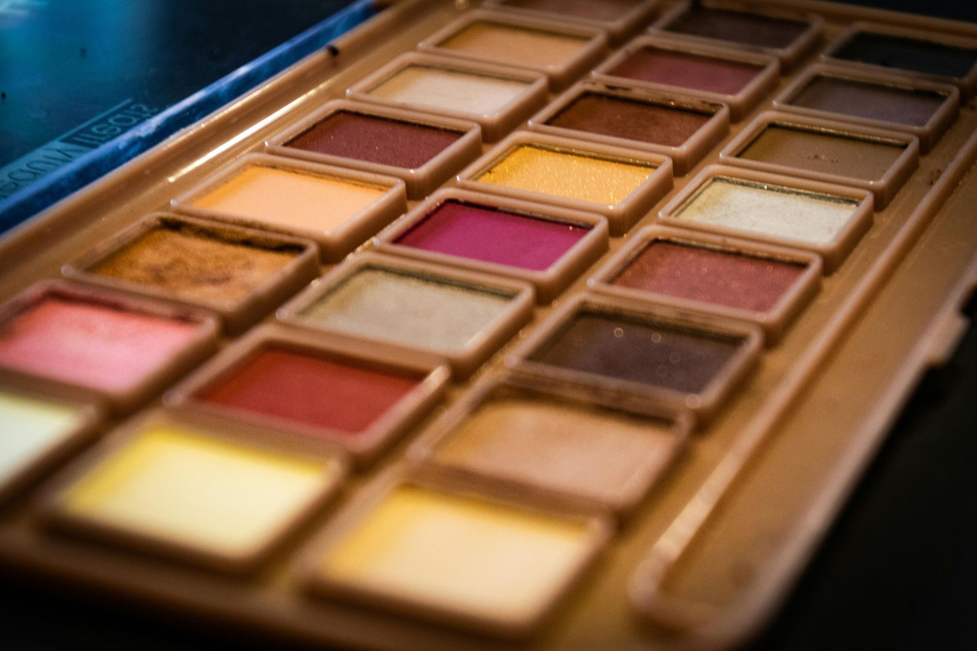 Close-up of a watercolor paint palette with rectangular paint cakes in various earth-tone colors.