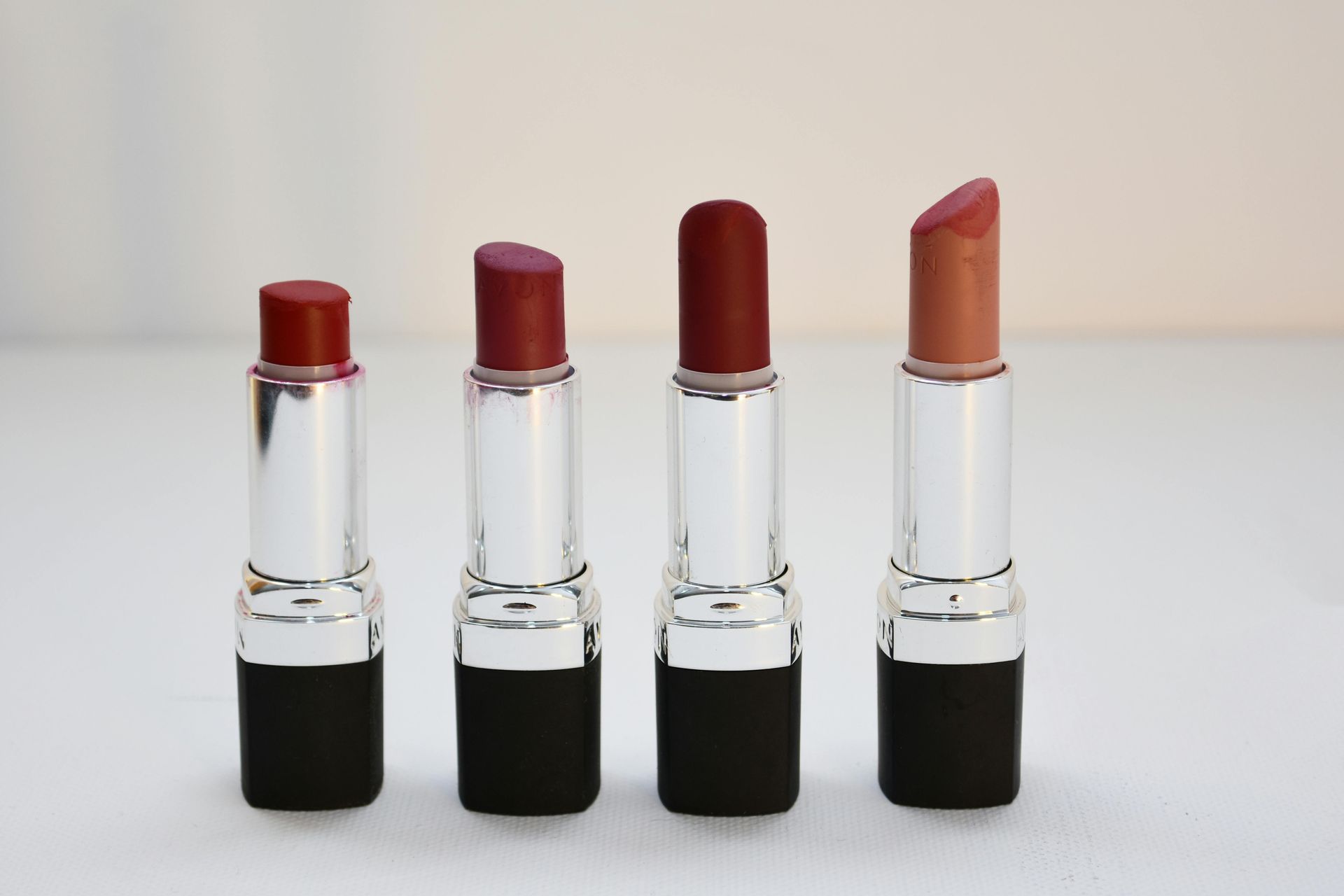 Four lipsticks in various shades of red and brown.