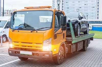 A tow truck with a car on the back is parked in a parking lot.