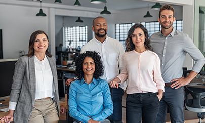 Three white trucks are parked in front of a warehouse.
