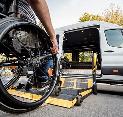 A man in a wheelchair is getting out of a van.